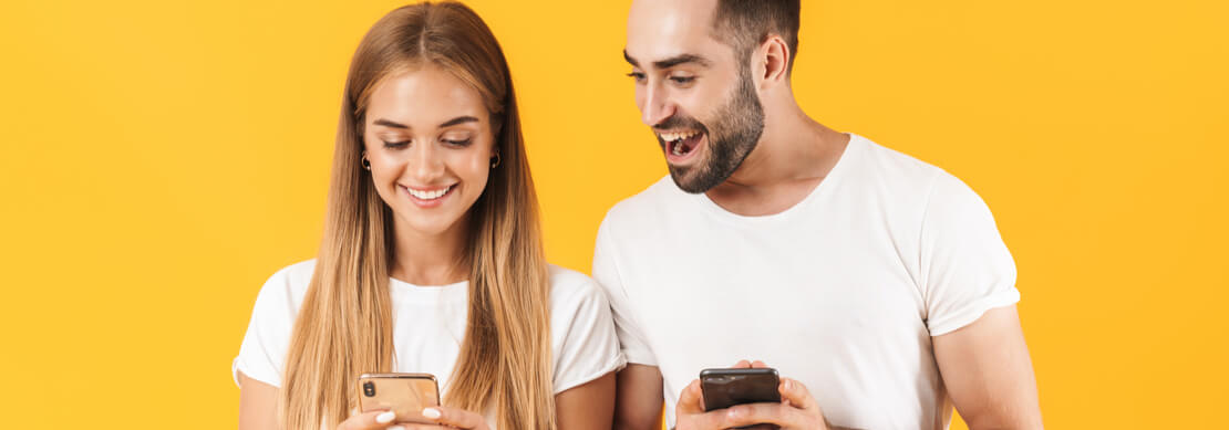 two happy people having fun playing on their phones