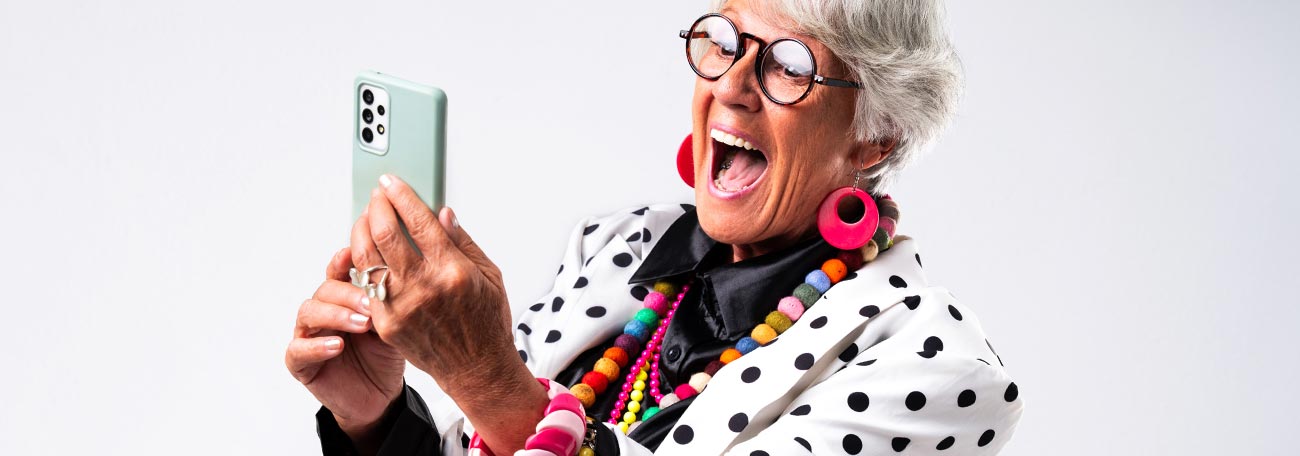 older woman dressed in bright colors having fun playing games on her phone